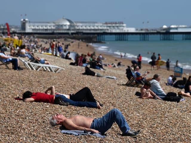 People relax on Brighton in southern England as temperatures rise across the country over the bank holiday weekend (Photo: GLYN KIRK/AFP via Getty Images)