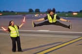 Airport ground handlers perform lively dance routine on runway.