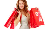 A shopper carrying red sale bags marked with a bold percentage sign, symbolising seasonal discounts and bargain hunting