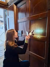 House manager Elena Williams inspects the historic witch's mark on the door of a dimly lit corridor at Hardwick Hall.