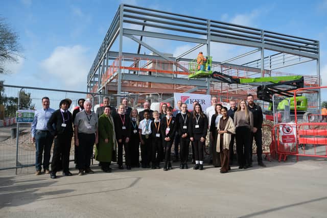 Students, staff and local representatives next to the structural steel frame of Mercia Academy's new building