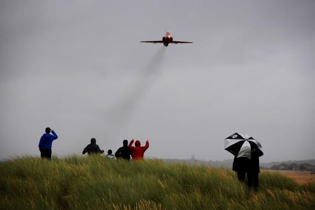 Enthusiasts on the sand dunes wave as the Red Arrows take off from Blackpool Airport in 2011