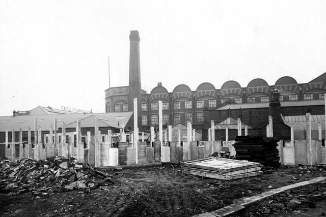 Wooden posts, concrete slabs and a pile of stones are visible. Wm. Blackburn and Co. Ltd. clothiers can be seen in the background on Springwell Road, Holbeck.