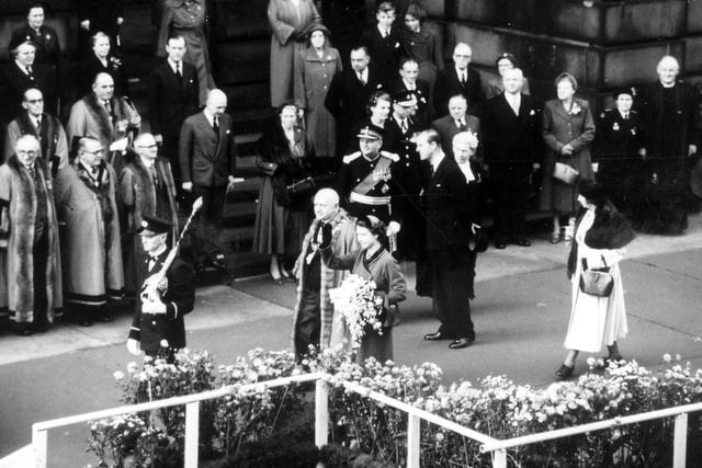 Her Majesty Queen Elizabeth II seen outside Morley Town Hall waving to onlookers. The mace bearer at the front is carrying the mace inverted as a mark of respect.
