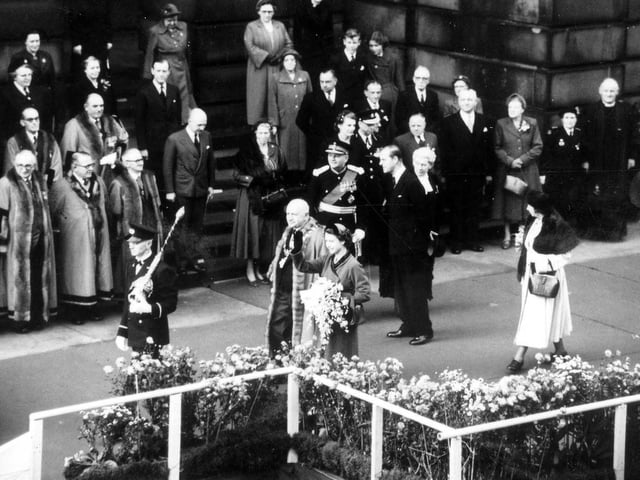 Her Majesty Queen Elizabeth II seen outside Morley Town Hall waving to onlookers. The mace bearer at the front is carrying the mace inverted as a mark of respect.