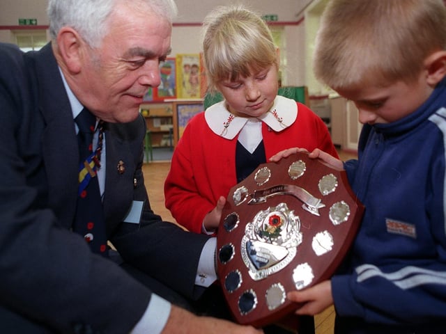 Pupils from Barley Hill Infants School study The Hammond Shield awarded to them by Michael Hammond of The Royal British Legion for selling the most poppies per head in Garforth.