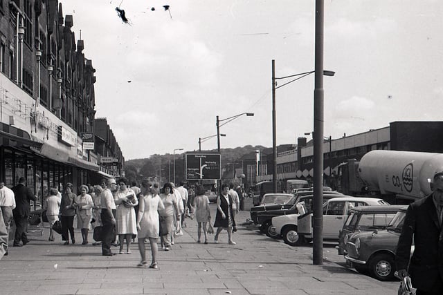 A busy Roundhay Road with Grandways supermarket on the left in 1972. A more modern shopping parade is on the right. The street is busy with shoppers, and cars are parked by the edge of the road.
