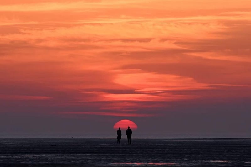 A couple watch the sunset on St Annes beach