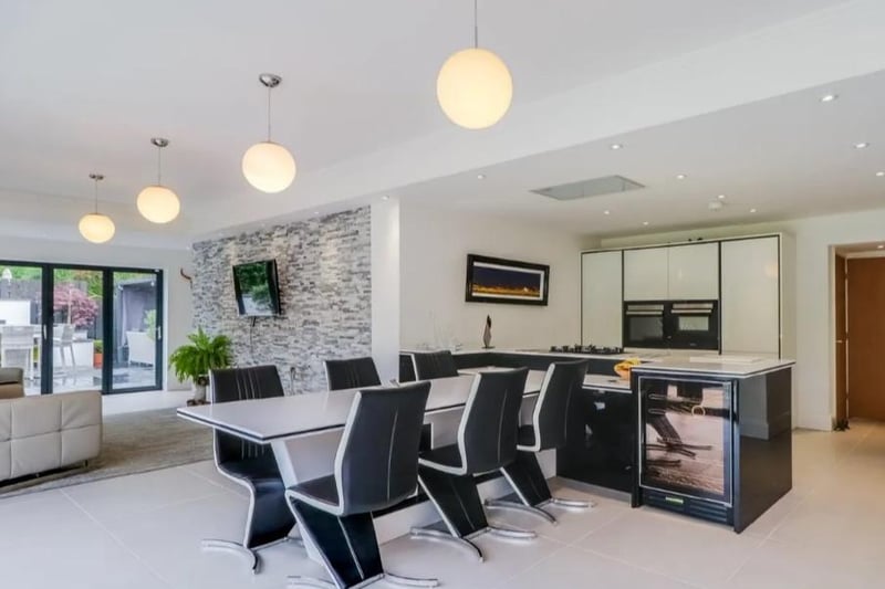 Finished in a striking contemporary with high gloss white fronted wall and base units with Corian worktops incorporating a double sink unit and five ring gas hob. Built-in oven and microwave, integrated extractor, integrated dishwasher, matching breakfast bar.