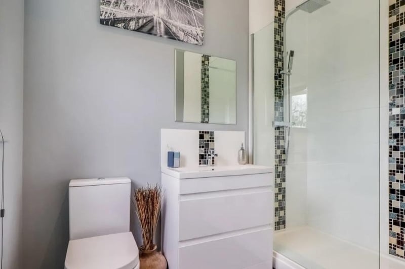 Fitted in a modern contemporary style with a wide shower cubicle with twin-head shower, vanity wash basin with drawers under and a low suite w.c. Tiled floor, part tiled walls, chrome ladder style heated towel rail, extractor fan and frosted window to the rear.