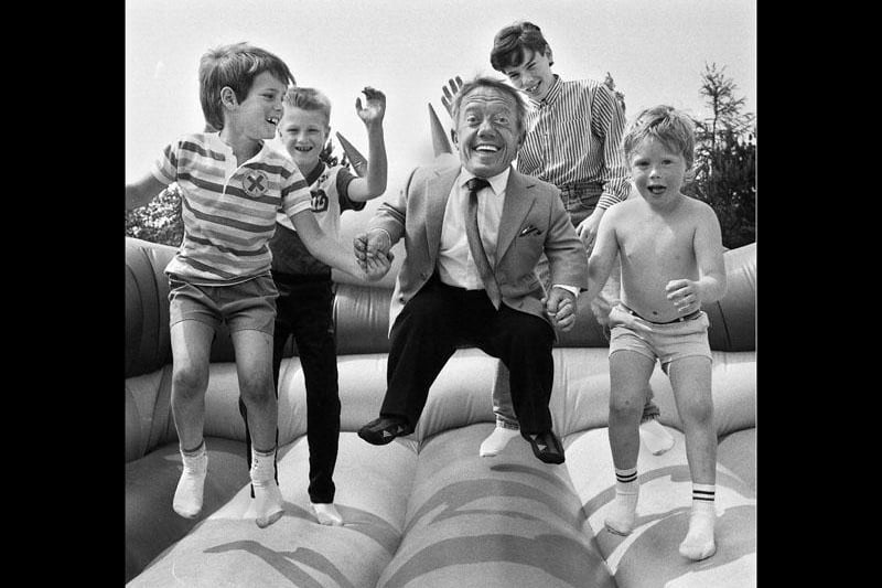 Going into orbit is R2D2, alias Kenny Baker, on the bouncy castle with young fans of Star Wars after he opened a fun day at Wigan Rugby Union Club in aid of the NSPCC on Saturday 20th of May 1989