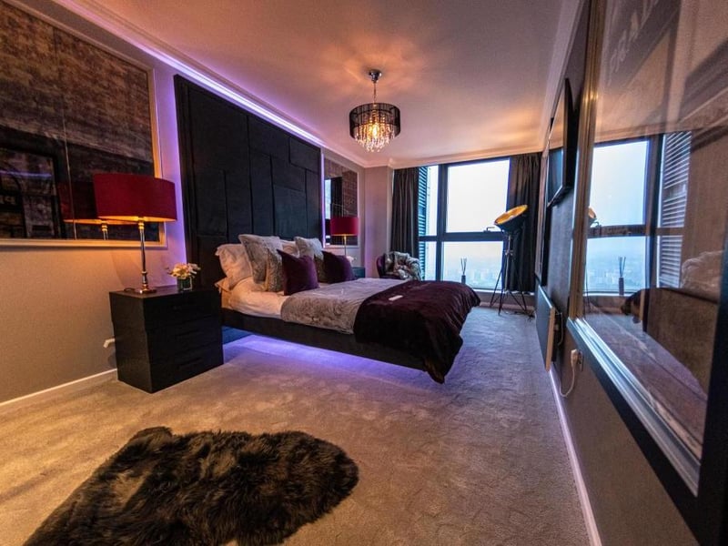 The first bedroom has a floating bed, large window and a ceiling decorated with a chandelier.