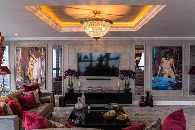 The living room is vast, fitted with an exquisite chandelier, tray ceiling and carpeted floor.
