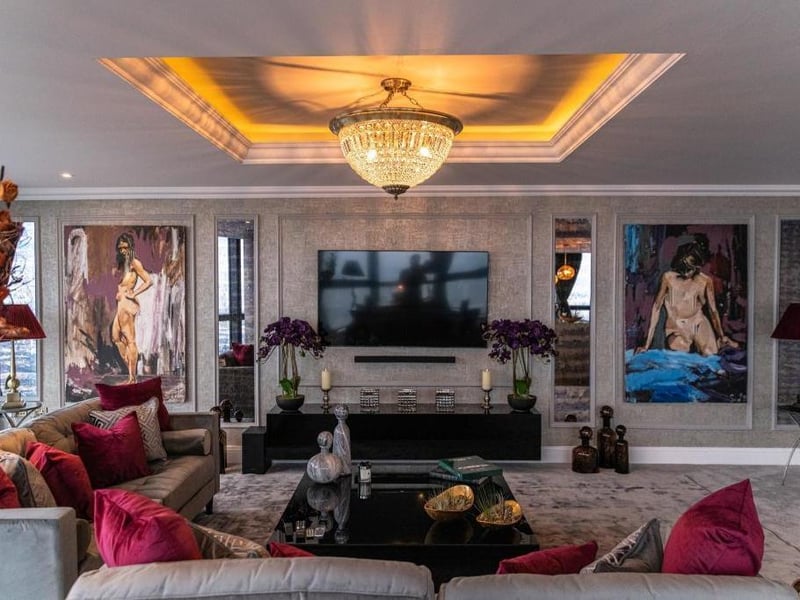The living room is vast, fitted with an exquisite chandelier, tray ceiling and carpeted floor.