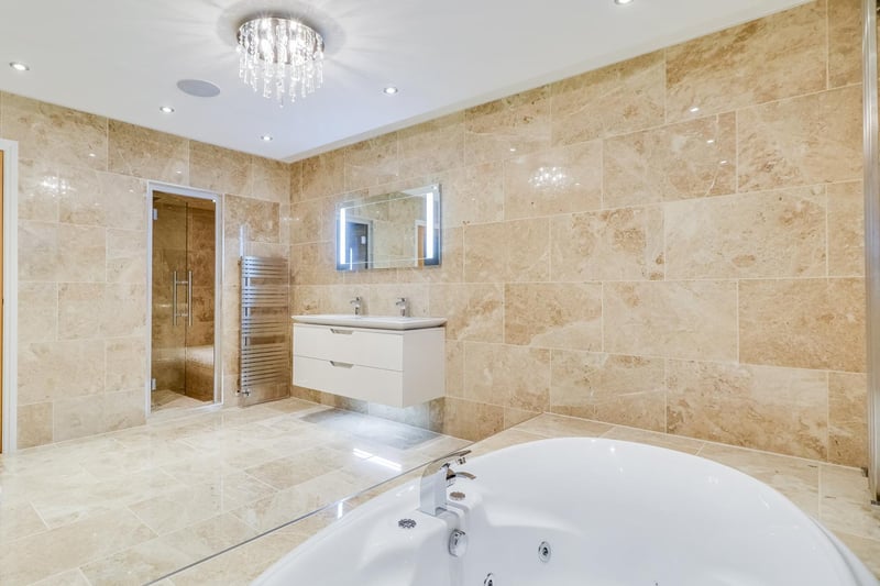 The marble tiled bathroom with a steam room leading off