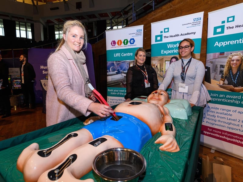 Rosie Burton from RJ Accounting Services tries out a life-sized operation game with Karen Gore and Olivia Dymond from Lancashire Teaching Hospitals at Lancashire Business Expo at Preston's Guild Hall.