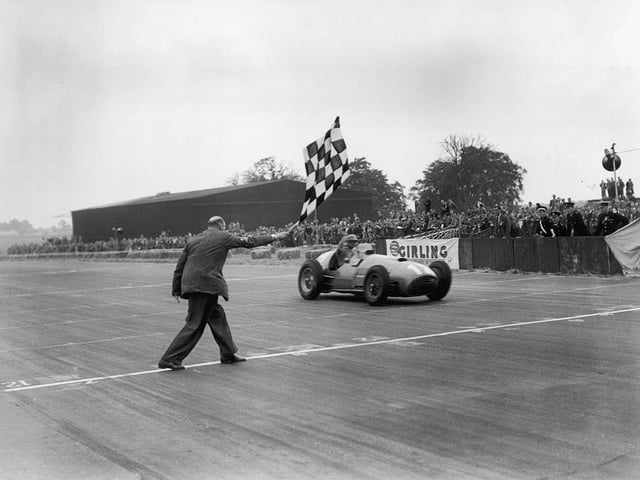 Froilan Gonzalez takes the winning flag in his Ferrari 375 at the 1951 British GP, beating fellow Argentian Juan Manuel Fangio into second place. The legendary Fangio went on to win five world titles between 1951 and 1957 a record only surpassed when Michael Schumacher won his fifth F1 crown in 2002