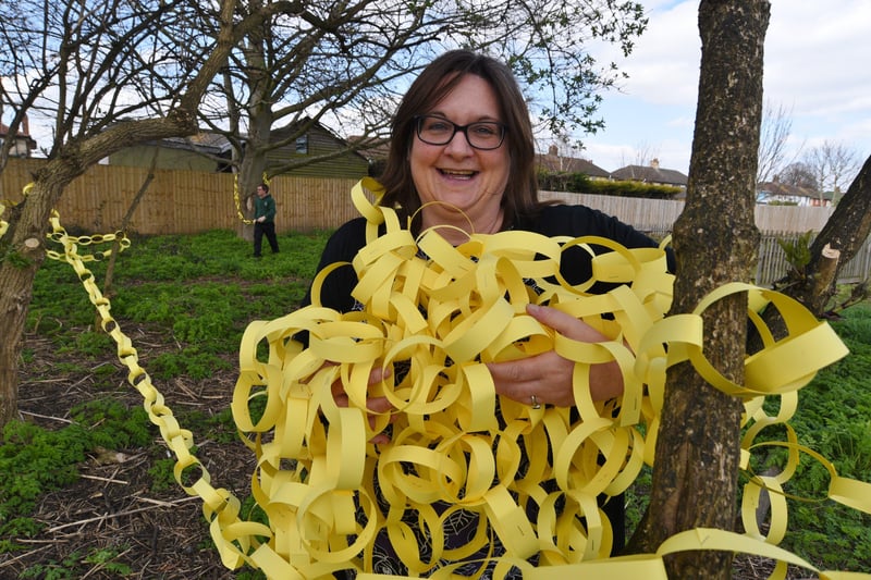 Woodston primary school hanging yellow paper chains around  trees on the school field to remember one year since the first Covid 19 lockdown.  Andrea Hatfield with paper chains EMN-210323-153057009