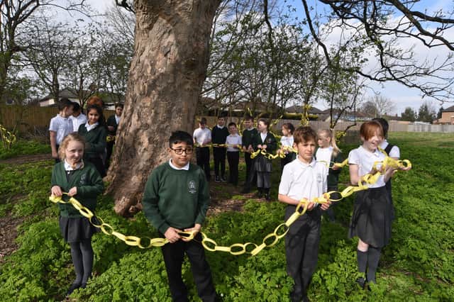 Pupils at Woodston primary school hanging yellow paper chains around  trees on the school field to remember one year since the first Covid 19 lockdown. EMN-210323-153121009