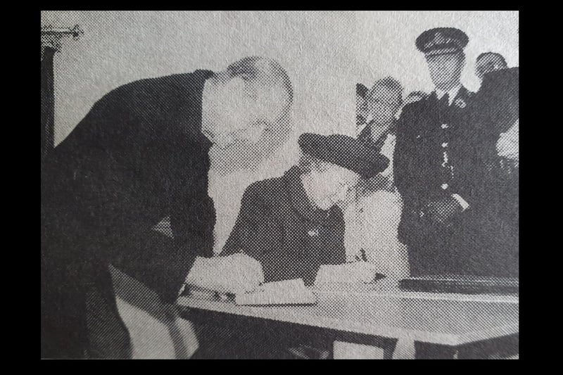 A grainy image of Prince Philip and the Queen signing the visitors' book during their visit to Warwick in 1996.