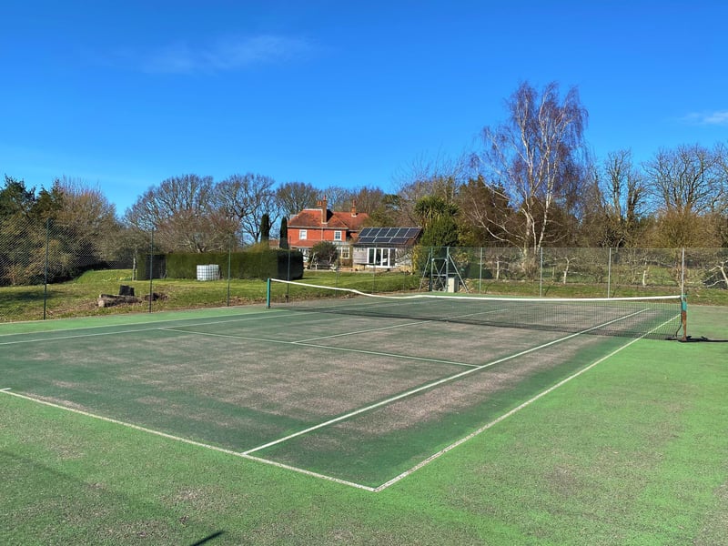 The grounds also include a tennis court (pictured), a four-acre paddock and a wildflower meadow