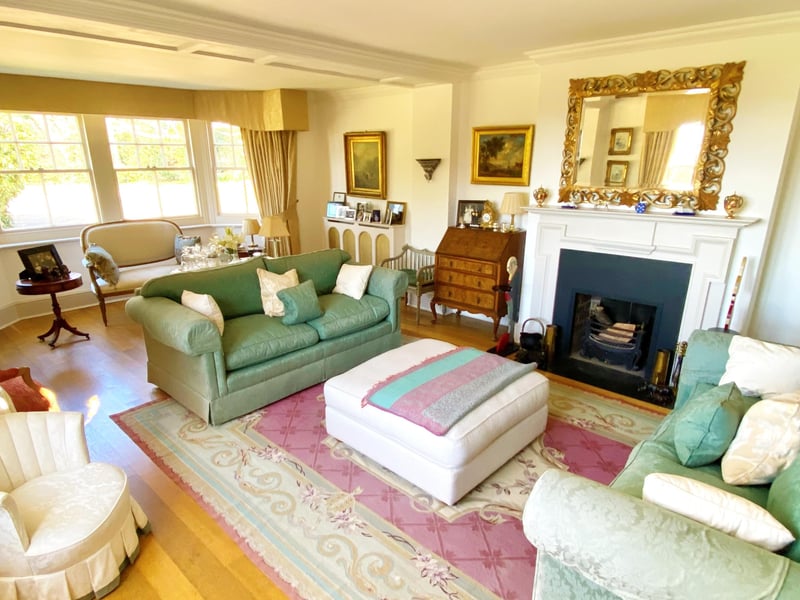 The drawing room with open fireplace and windows overlooking the garden