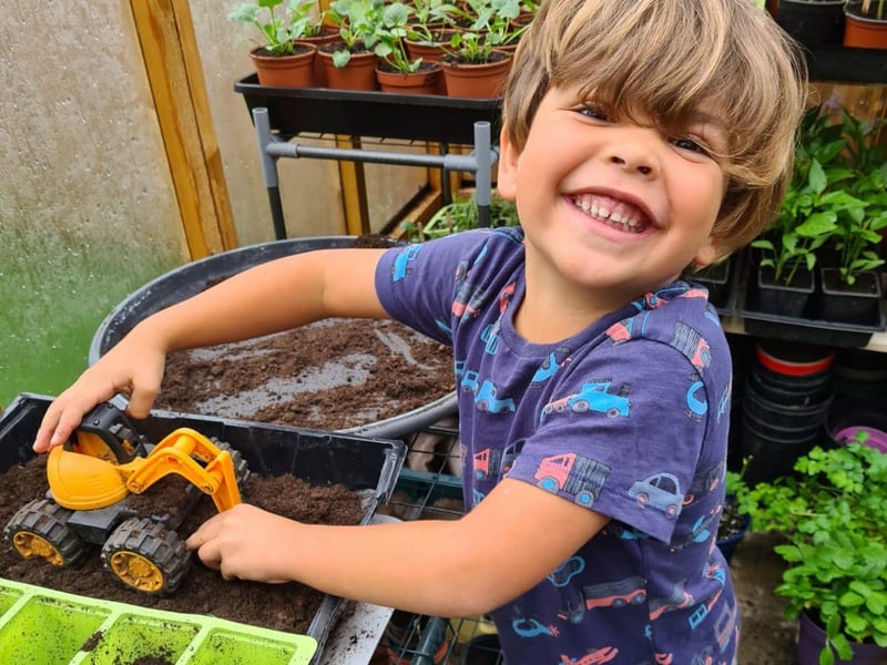 Douglas uses his toy truck to dig the soil