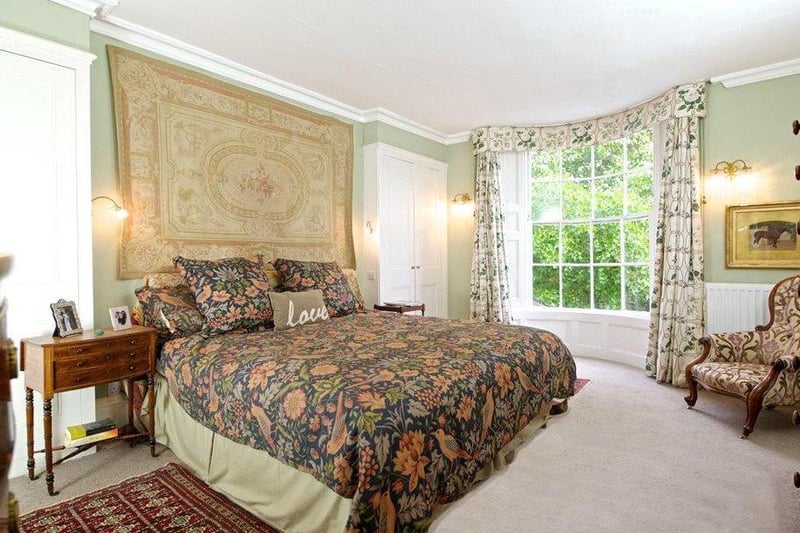 The master bedroom has double wardrobes either side of the bed, original coving, and a Regency full height bow window overlooking the rear garden