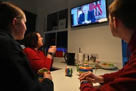 A family gather around the television to watch Britain's Prime Minister Boris Johnson give a televised message to the nation from 10 Downing Street in London (Photo by PAUL ELLIS/AFP via Getty Images)