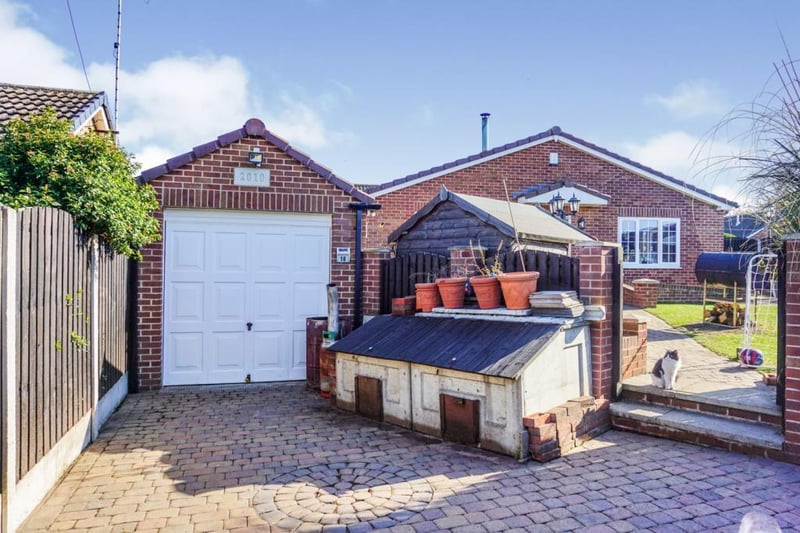 Gated driveway leading to the brick-built garage, with ample parking for two vehicles