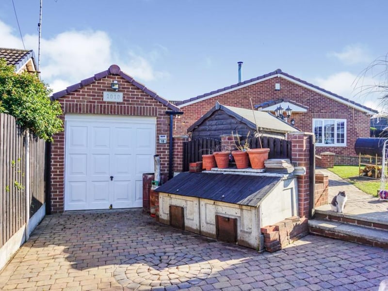 Gated driveway leading to the brick-built garage, with ample parking for two vehicles