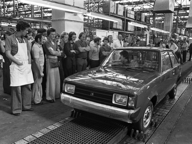Workers at Linwood watch as the first new Chrysler Sunbeam car rolls of the production line/assembly line in August 1977.