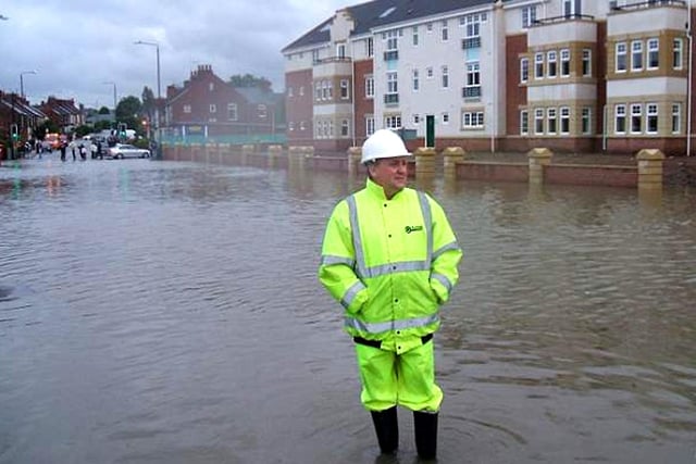 A contractor wading through the flooded Derby Road in Chesterfield while Barratt's new properties at The Spires remained high and dry.