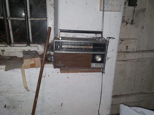 An old radio sits among debris on a windowsill
