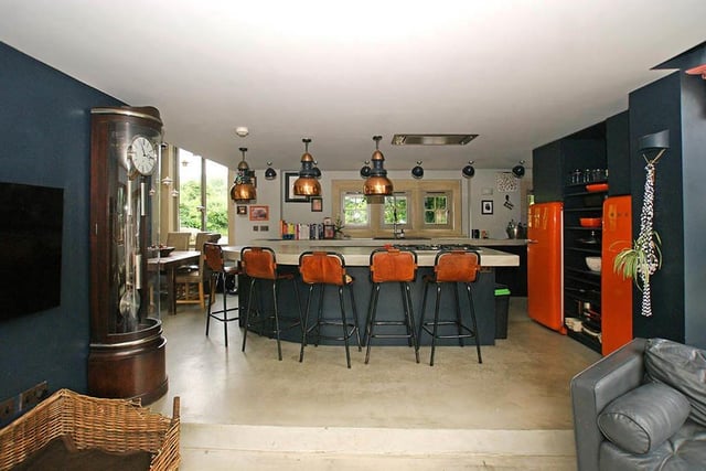 An island serves as a breakfast bar and contains a built-in gas hob. There's a formal dining area at the side of the kitchen.