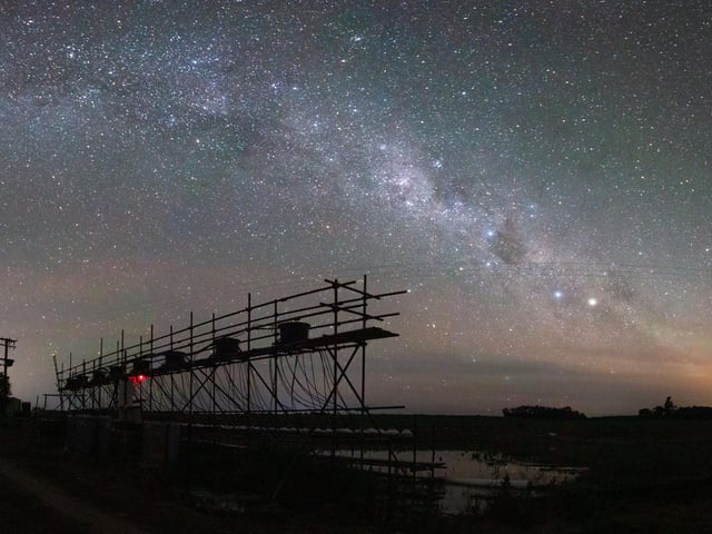 Category 5 – Ecology in Action
Showcasing the practice of ecology in action

Student winner: James Orr, Trinity College Dublin

Constant Flow: This photograph is a panorama made up of multiple long-exposure photographs of the Milky Way above an experimental stream system made up of 128 mesocosms. As part of my PhD, I helped to run a multiple-stressor experiment testing the individual and combined effects of different climate-change stressors on freshwater food webs. Each of the 128 mesocosms, or medium worlds, had a diverse ecosystem from bacteria to fish. Pumps constantly pushed water from the nearby river up to eight main water tanks and then down through our mesocosms for five weeks straight, day and night.