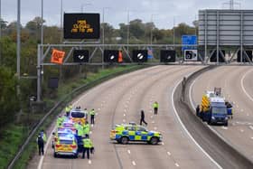 Police officers attempt to stop an activist as they put up a banner reading "Just Stop Oil" atop an electronic traffic sign along M25. Just Stop Oil, an environmental activist group, has staged a series of protests across London in recent weeks. (Photo by Leon Neal/Getty Images)