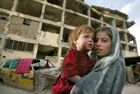 Storai, age 7 holds her sister Sameera age 2 1/2 years stand outside their home in the ruins of a vacant building in Kabul, Afghanistan. (Photo by Paula Bronstein/Getty Images)