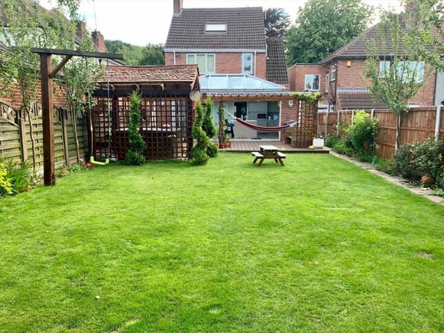 The large garden has a lawn and deck area.