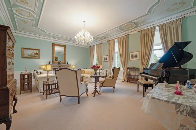 The sitting room is one of seven reception rooms and offers eye-catching decorative plasterwork on the ceiling, the colours of which are complemented in the paintwork on the walls and in the furnishings.