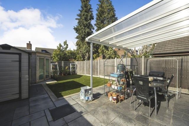 Our final photo shows the back garden from a different angle. In the foreground is a pleasant patio area with seating, while in the background is a summer house.