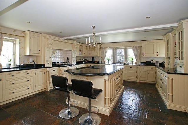 This opulent room has Chinese slate on the floor, fitted storage units with polished granite work surfaces and a central island that creates a breakfast bar with cupboards below and two under-counter fridges. A twin Belfast style sink is  contained within the work surface. The kitchen features luxury branded appliances including a Bosch 12-place setting dishwasher and a gas fired Aga with twin lidded hot plates and three ovens.