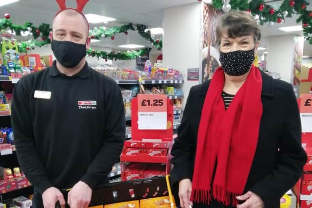 Manager of Spar Bakewell Steve McMahon handing over biscuits for the Christmas hampers to Heather Thomas.