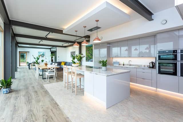 Flow-through rooms give the house an airy feel with gloss cabinets in the kitchen reflecting the light coming through the  floor to ceiling windows. (photo: Channel 4)