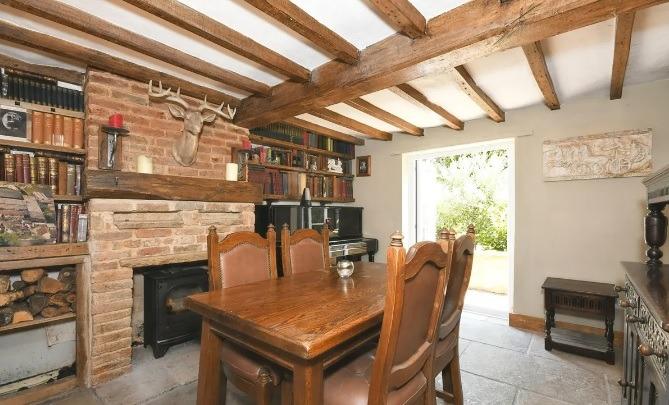 The dining room has original oak beams on the ceiling and French doors opening to the gardens. A multi-fuel burner sits in a brick fireplace with timber mantel over.