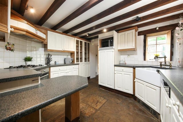 Ancient and modern meet in the heart of the home where the kitchen contains exposed ceiling beams and stone flag flooring and is fitted with Shaker-style units and an integrated oven.