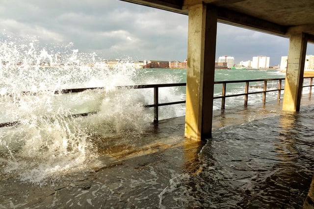 Waves crash in and flood the sunny walkway at Old Portsmouth.