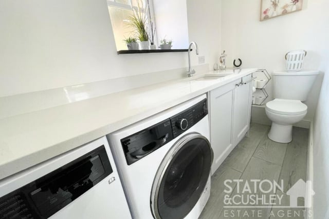 Just off the kitchen/diner is this handy utility room, which has space for a washing machine and tumble dryer. It is fitted with base units and a quartz worktop, while a low-level WC sits at the far end.