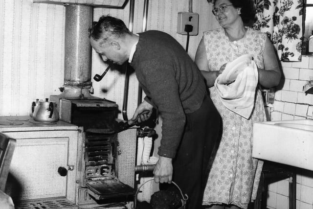 Miner Frankie Vaughan, of the Swadlincote Colliery, stokes the stove at his home with coal, while his wife Betty looks on in 1962. Frankie won the George Medal for rescuing two trapped miners.  (Photo by Keystone Features/Getty Images)
