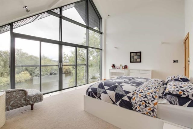The main bedroom has carpeted flooring with underfloor heating, fitted sliding door wardrobes, wall light fixtures, access to an en-suite, full height double glazed windows and a sliding door providing access to a Juliet balcony.